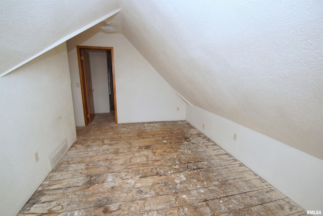705 Brady St, Davenport, IA 52803 - additional living space featuring vaulted ceiling, visible vents, a textured ceiling, and wood-type flooring