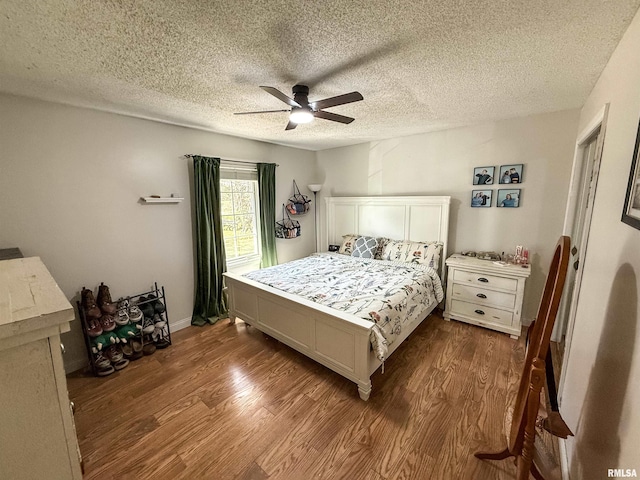 bedroom featuring ceiling fan, dark wood-type flooring, and a textured ceiling