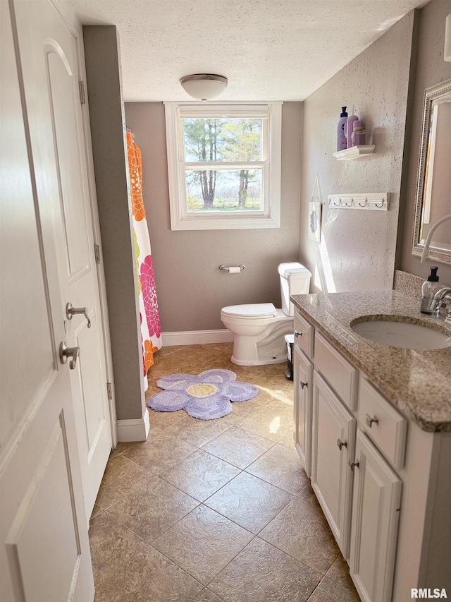 bathroom with curtained shower, toilet, vanity, baseboards, and a textured ceiling