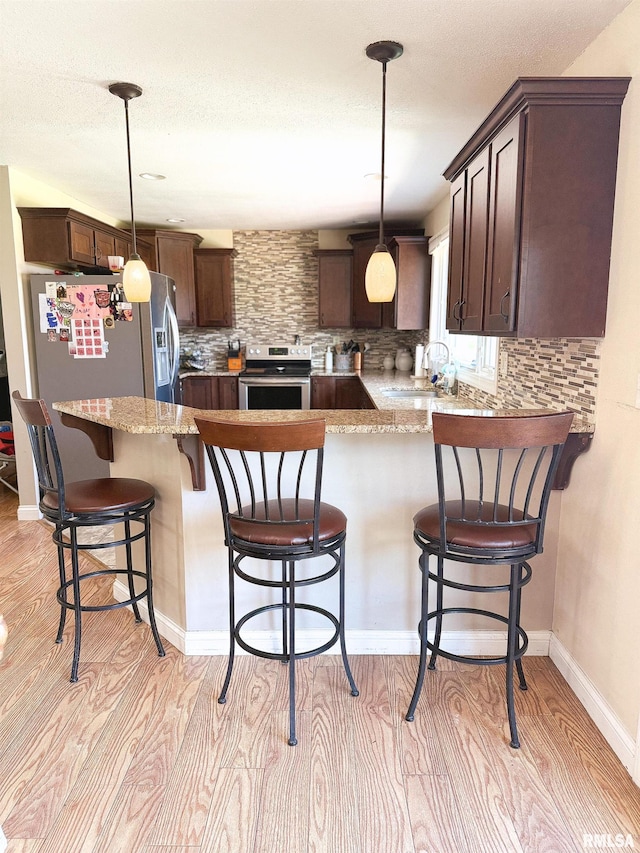 kitchen with dark brown cabinetry, light wood-style flooring, a sink, and appliances with stainless steel finishes