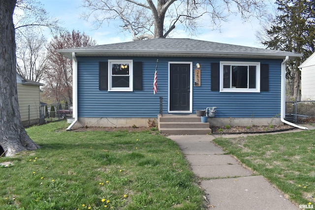 bungalow featuring a front lawn and roof with shingles