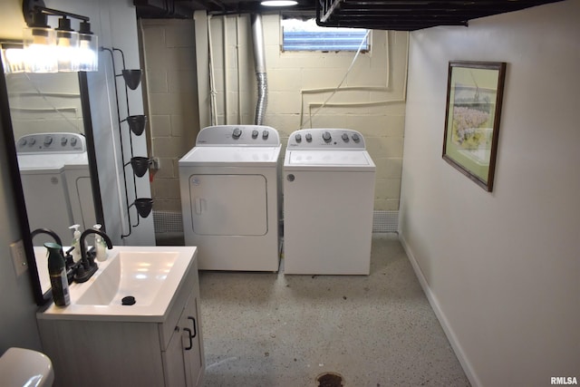 washroom featuring washing machine and dryer, baseboards, a sink, and concrete block wall