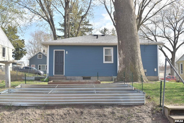 rear view of house featuring entry steps, roof with shingles, and fence