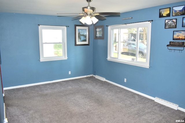 unfurnished room with baseboards, dark colored carpet, visible vents, and a healthy amount of sunlight