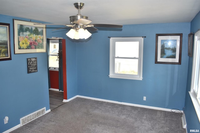 carpeted spare room with visible vents, baseboards, and ceiling fan