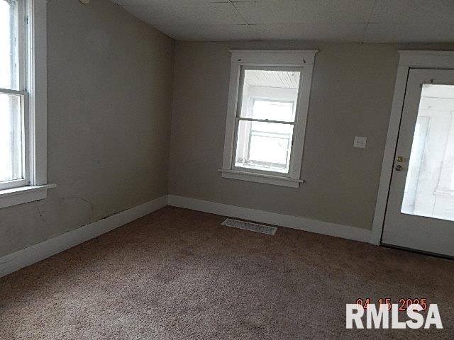carpeted spare room with plenty of natural light, visible vents, and baseboards