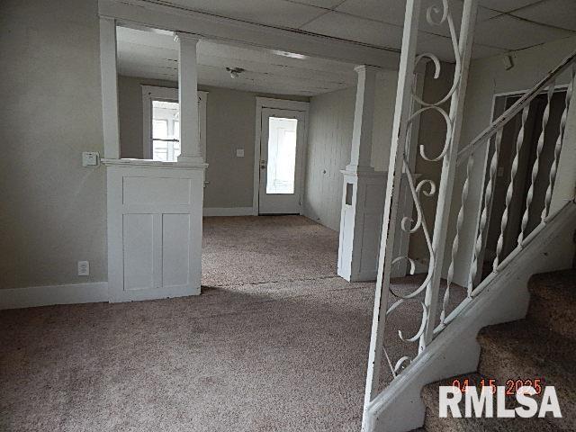 interior space with baseboards, carpet, and ornate columns