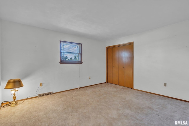 unfurnished bedroom featuring baseboards, visible vents, carpet, and a closet