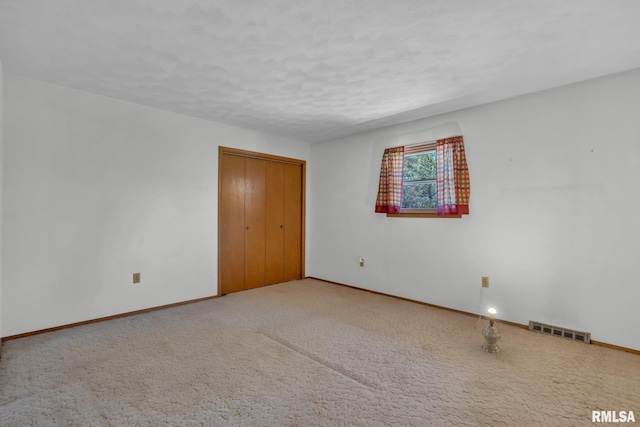 carpeted empty room with baseboards, a textured ceiling, and visible vents