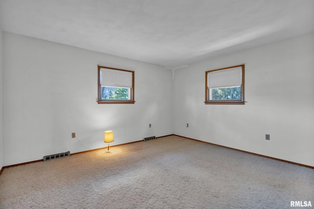 carpeted spare room with visible vents, baseboards, and a healthy amount of sunlight