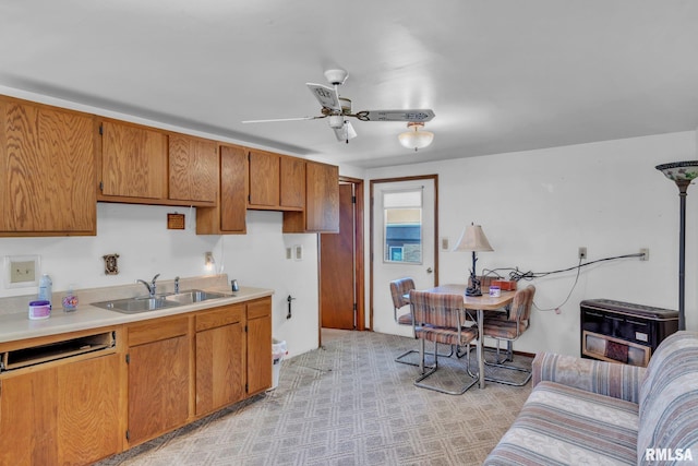 kitchen featuring brown cabinetry, light countertops, a sink, and ceiling fan