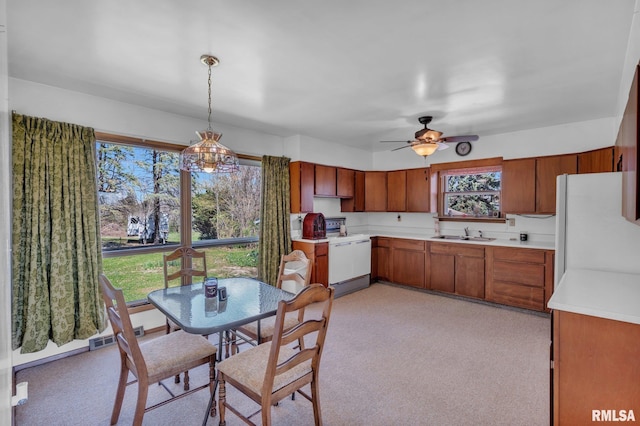 kitchen featuring a ceiling fan, a sink, brown cabinets, white appliances, and light countertops