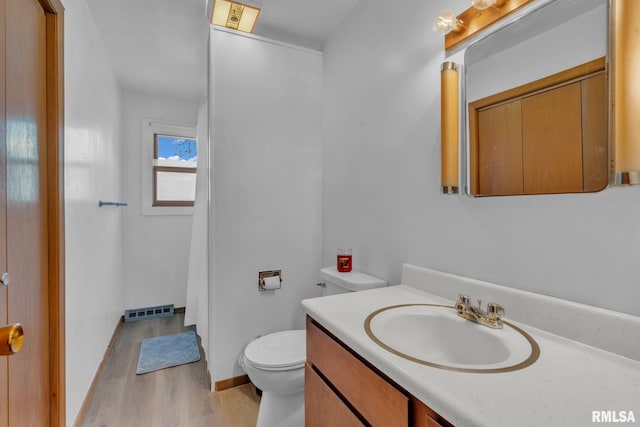 bathroom with wood finished floors, visible vents, toilet, vanity, and baseboards