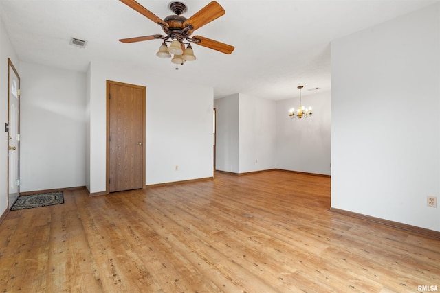 empty room with wood-type flooring, baseboards, visible vents, and ceiling fan with notable chandelier