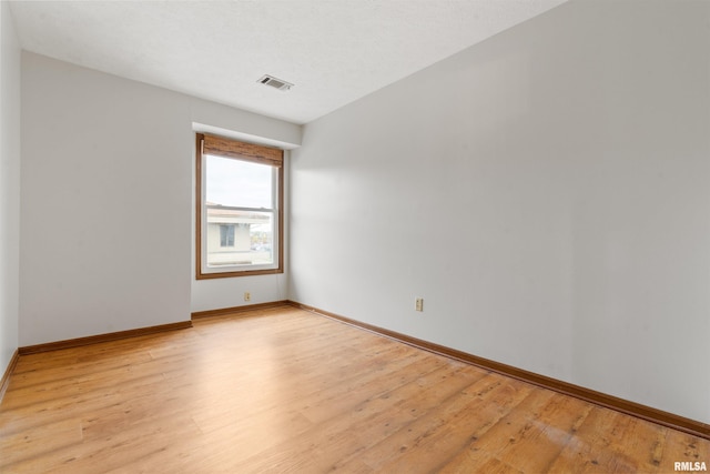 unfurnished room with baseboards, light wood-style flooring, and visible vents
