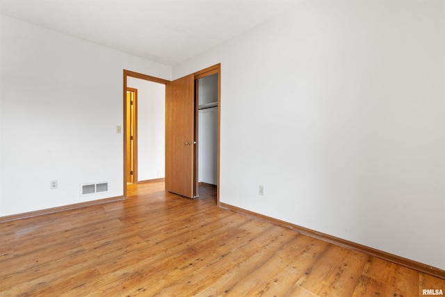unfurnished bedroom featuring a closet, light wood-style floors, visible vents, and baseboards