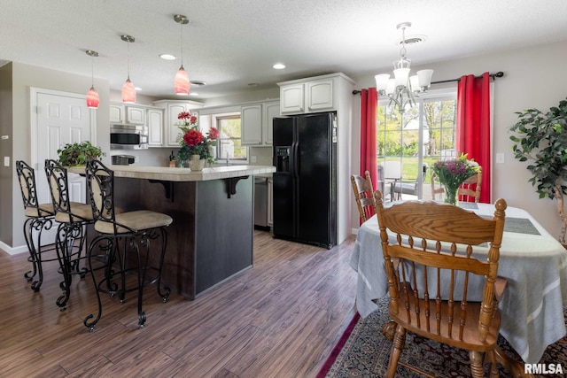 505 W College St, Energy, IL 62933 - kitchen with stainless steel microwave, a notable chandelier, white cabinetry, black fridge with ice dispenser, and a breakfast bar