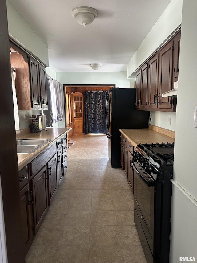 kitchen featuring black appliances, dark brown cabinetry, under cabinet range hood, and a sink