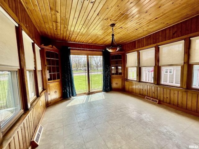 unfurnished room with wood ceiling, visible vents, and wooden walls