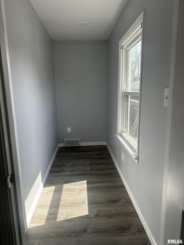empty room featuring visible vents, baseboards, and dark wood-style flooring
