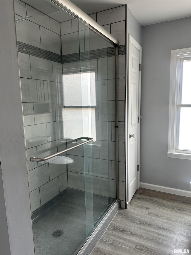 full bath featuring a stall shower, baseboards, wood finished floors, and a healthy amount of sunlight