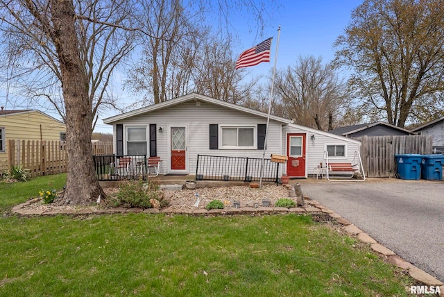 view of front facade with a front lawn, aphalt driveway, and fence