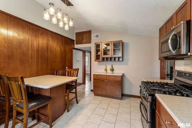 kitchen featuring vaulted ceiling, a kitchen breakfast bar, stainless steel appliances, and light countertops