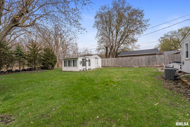 view of yard featuring central AC, fence, and an outbuilding