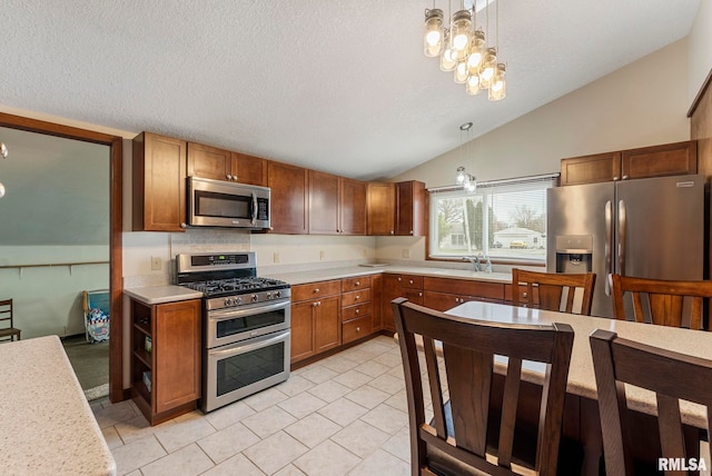 kitchen with a sink, lofted ceiling, brown cabinetry, light countertops, and appliances with stainless steel finishes