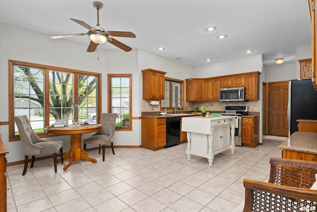 kitchen featuring a sink, brown cabinetry, stainless steel appliances, a ceiling fan, and tasteful backsplash