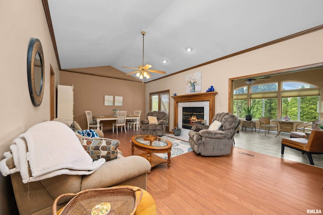 living room with plenty of natural light, visible vents, crown molding, wood finished floors, and lofted ceiling