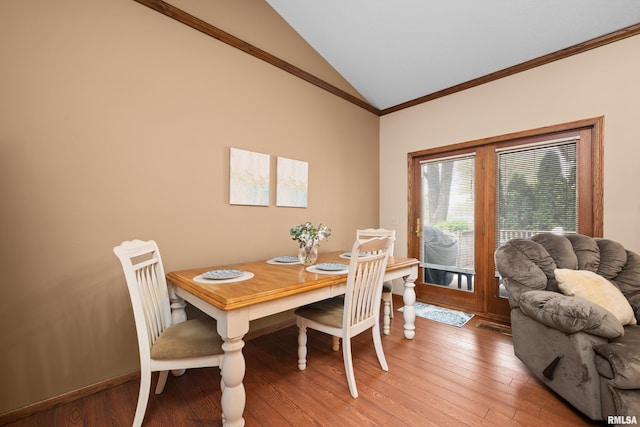 dining area featuring crown molding, light wood-style flooring, and vaulted ceiling
