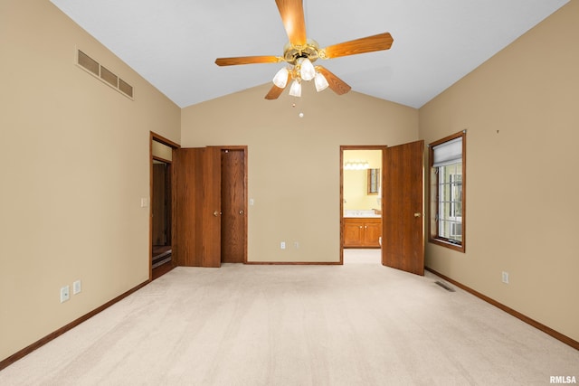 unfurnished bedroom featuring vaulted ceiling, ensuite bath, light colored carpet, and visible vents