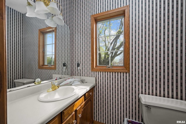 bathroom with a healthy amount of sunlight, vanity, toilet, and wallpapered walls
