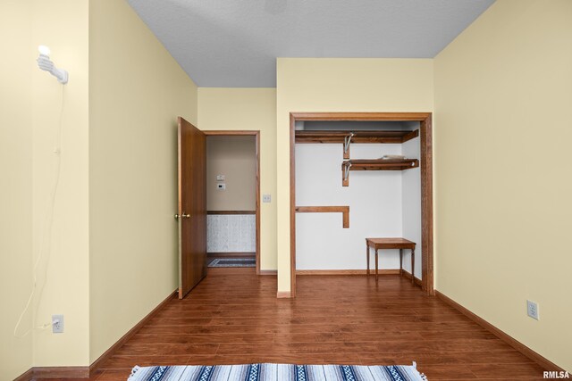 unfurnished bedroom featuring baseboards and dark wood-style flooring
