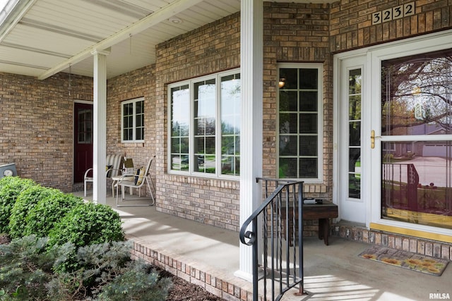 doorway to property featuring brick siding and covered porch
