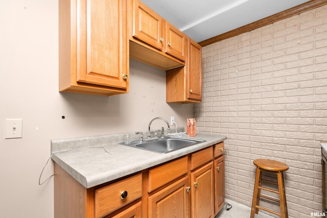 kitchen with light countertops, brick wall, and a sink