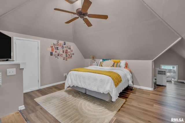 bedroom featuring lofted ceiling, a ceiling fan, wood finished floors, and baseboards