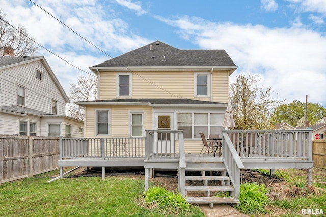 rear view of property with a shingled roof, a wooden deck, a fenced backyard, and a lawn