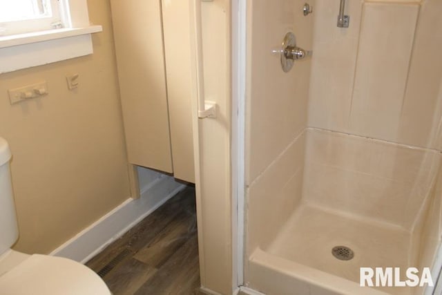 full bath with baseboards, wood finished floors, a shower stall, and toilet