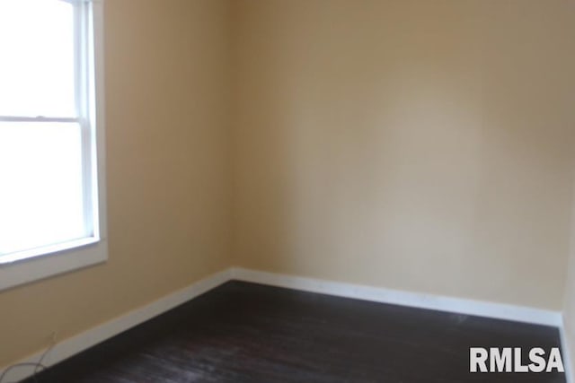 unfurnished room with baseboards and dark wood-style flooring