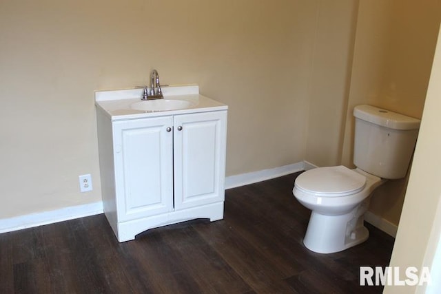 bathroom featuring wood finished floors, baseboards, vanity, and toilet