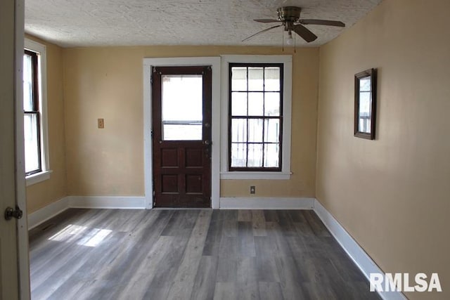 interior space with ceiling fan, baseboards, wood finished floors, and a textured ceiling