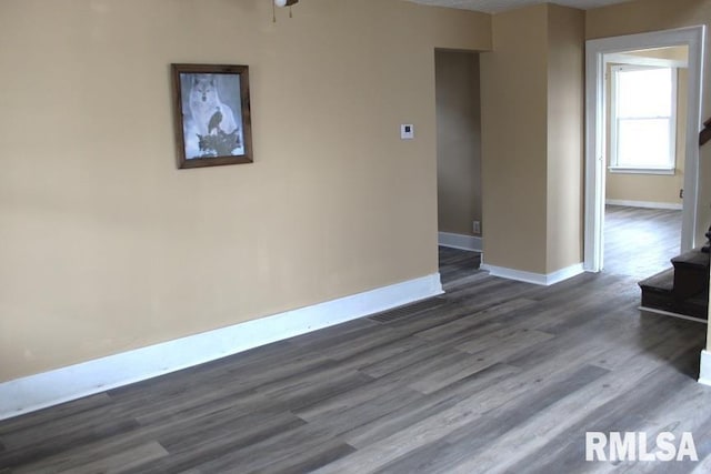 unfurnished room featuring stairway, baseboards, and dark wood-style flooring