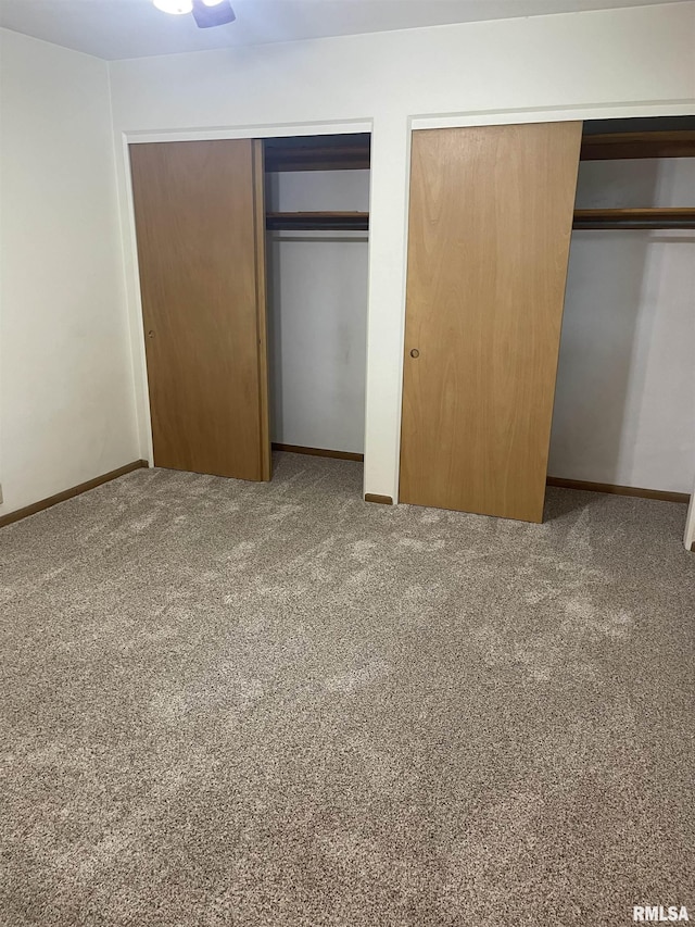 1725 Elmwood Ln, Bettendorf, IA 52722 - unfurnished bedroom with two closets, carpet flooring, and baseboards