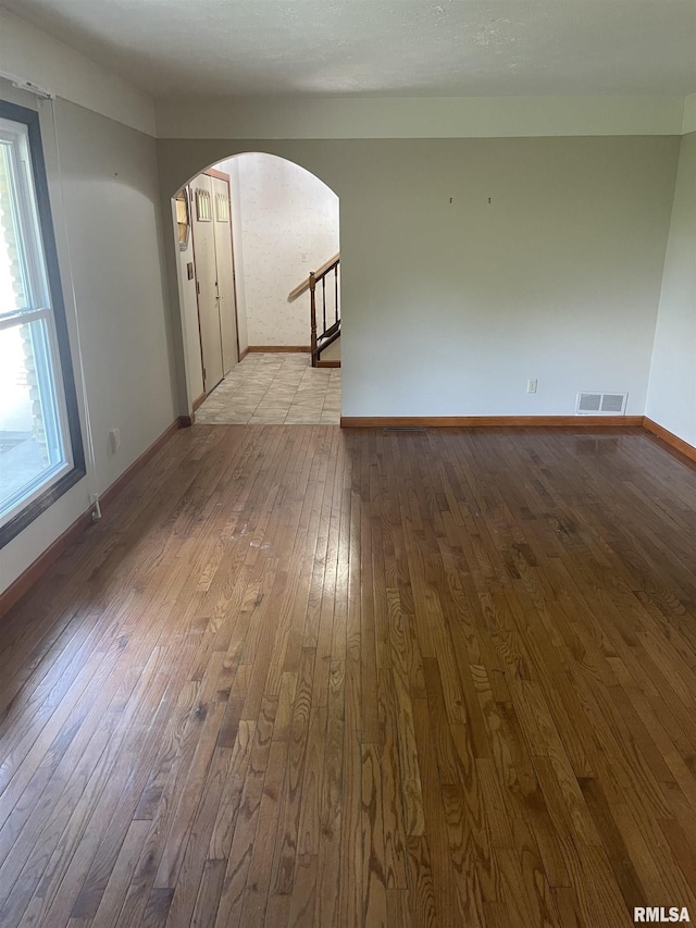 5833 Taylor St, Davenport, IA 52806 - unfurnished living room with wood-type flooring, arched walkways, baseboards, and a textured ceiling