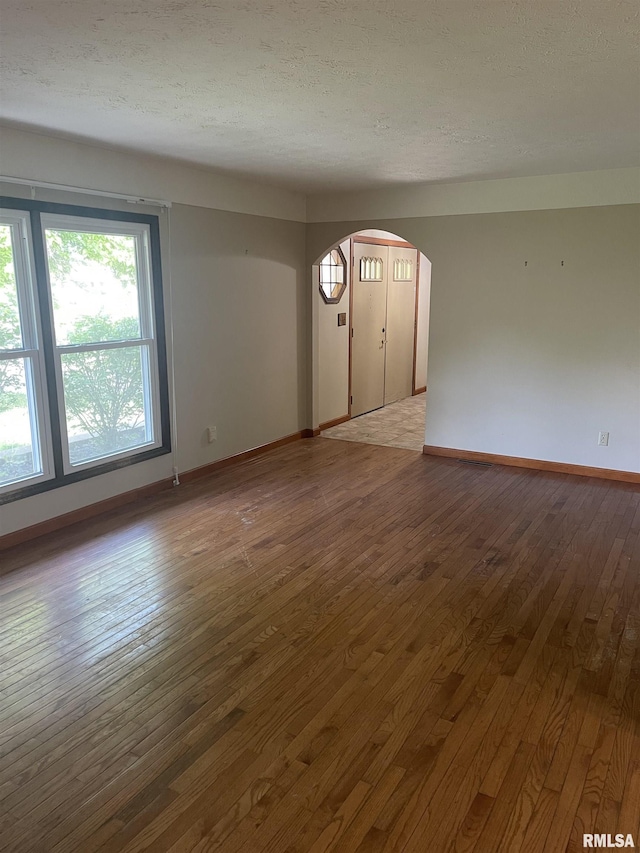 5833 Taylor St, Davenport, IA 52806 - unfurnished living room with wood-type flooring, arched walkways, baseboards, and a textured ceiling