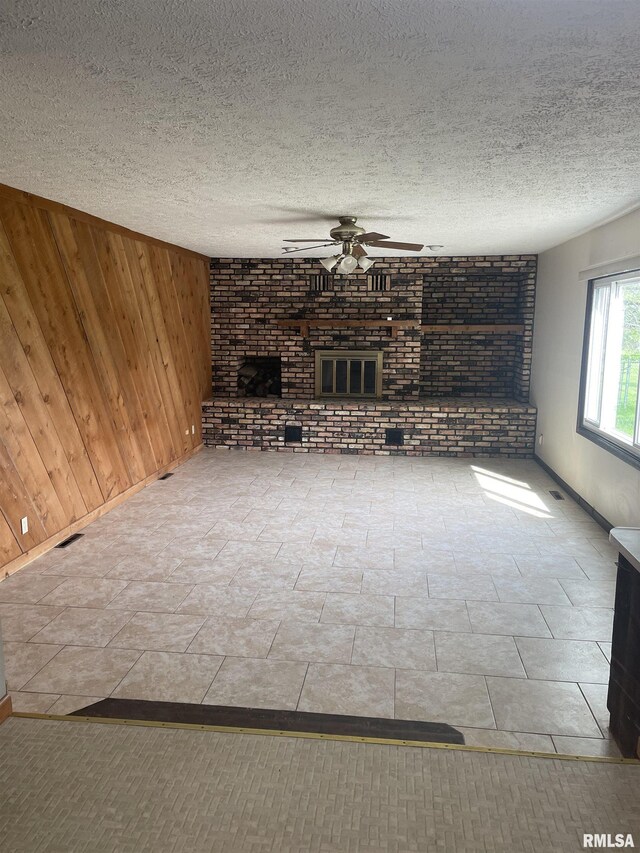 5833 Taylor St, Davenport, IA 52806 - unfurnished living room with a ceiling fan, wooden walls, a brick fireplace, brick wall, and baseboards