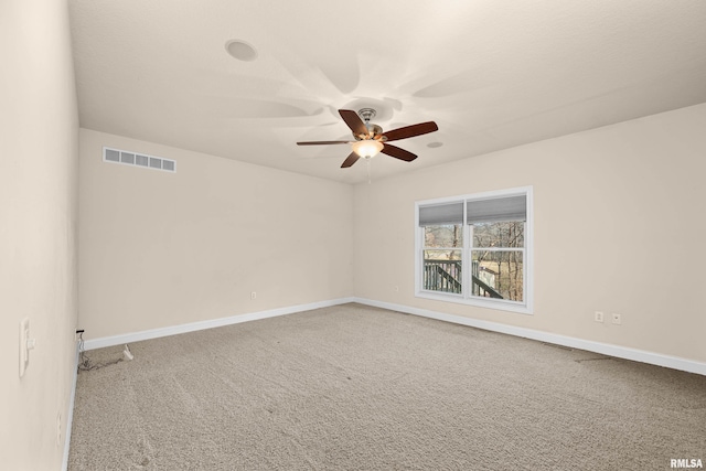 empty room with baseboards, visible vents, carpet floors, and ceiling fan