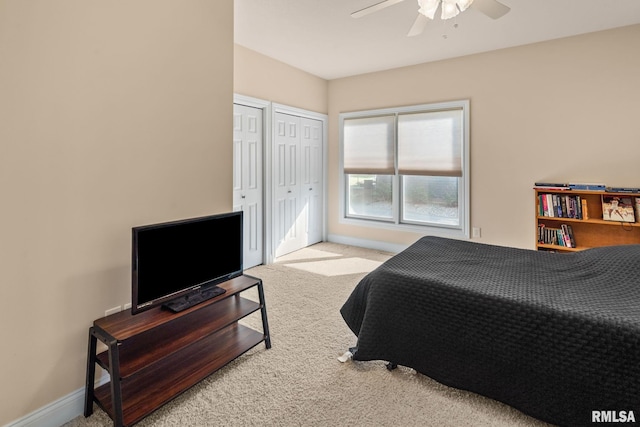 bedroom with two closets, ceiling fan, baseboards, and carpet flooring